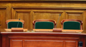 Vista interior del edificio del Tribunal Constitucional italiano, con la sala vacía y los emblemas oficiales visibles.