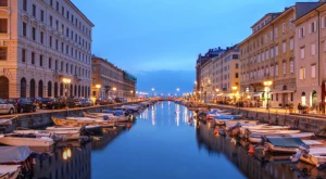 Paisaje italiano con pequeñas embarcaciones en un canal y arquitectura histórica al fondo, representando la conexión entre territorio, movilidad y vida cotidiana en Italia