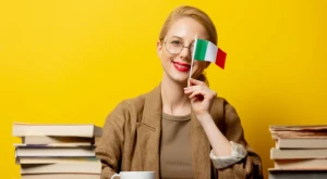 Chica con libros de estudio en la mano frente a la bandera italiana.