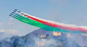 Aircraft flying in formation leave green, white, and red contrails forming the Italian tricolor in the sky.