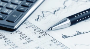 Calculadora, lápiz y documentos con cálculos financieros sobre una mesa