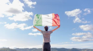 Person holding an Italian flag outdoors with the fabric fully extended.