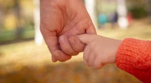An adult holding a child’s hand, symbolizing protection and family care