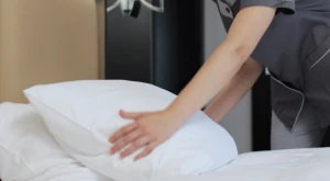 Lavoratrice domestica mentre rifà il letto in un’abitazione privata.