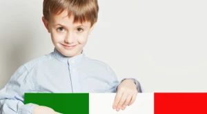 Niño sosteniendo una bandera italiana con ambas manos.