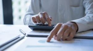 Person doing tax calculations with documents and a calculator