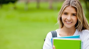 Female student standing and holding her notebooks.