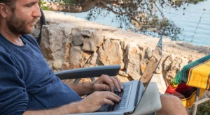 Persona che lavora al computer portatile sulla spiaggia