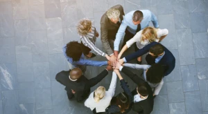 A group of people placing their hands together in the center as a sign of teamwork and collaboration.