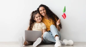 A mother and her young daughter holding an Italian flag, symbolizing the transmission of Italian citizenship to children born abroad.